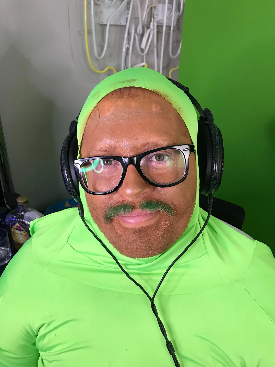 Wubby in a green suit and headphones